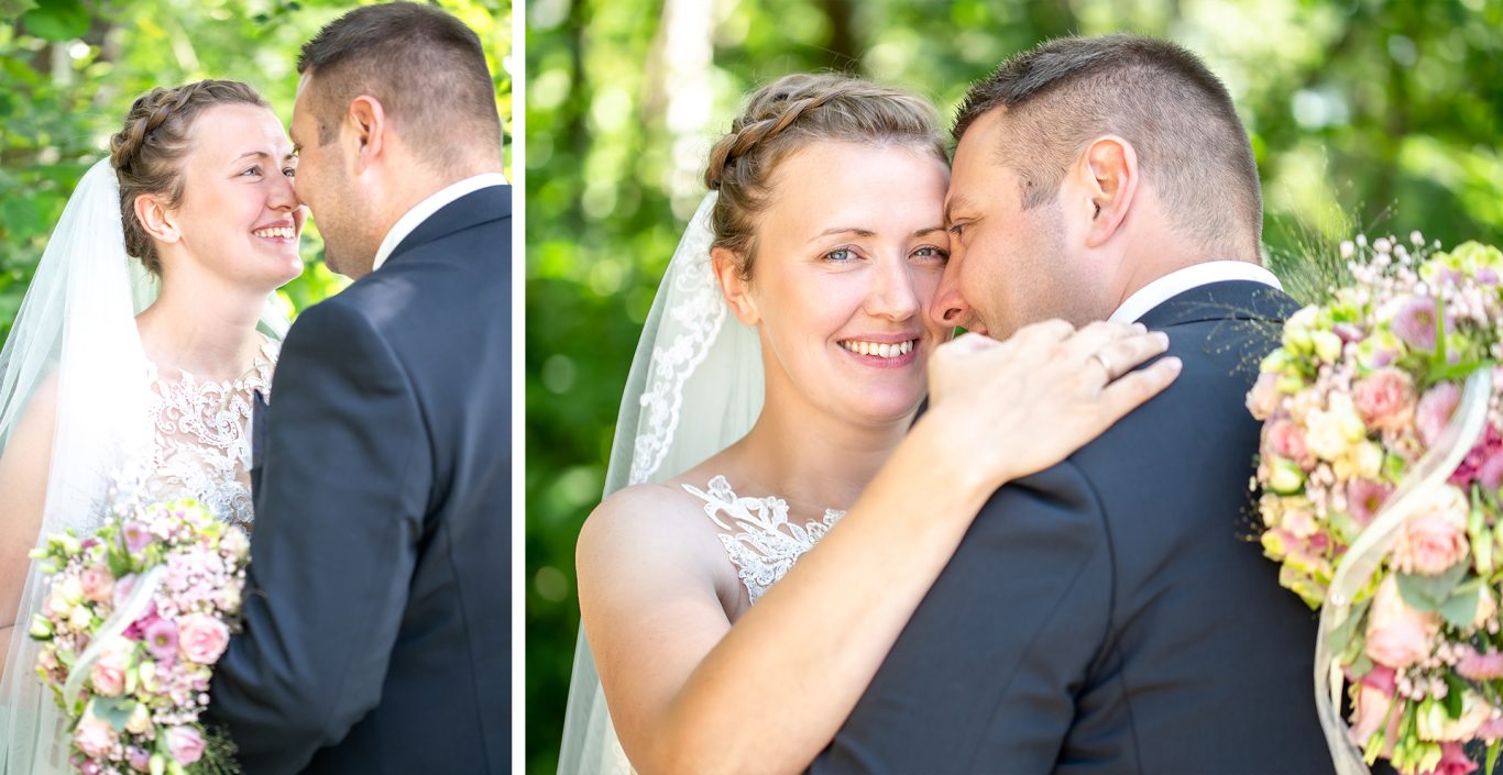 Braut und Bräutigam umarmen sich in einer grünen, sonnigen Umgebung.